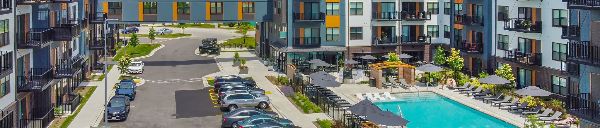 aerial of the exterior of the ruby apartments with pool, skywalk, and parking