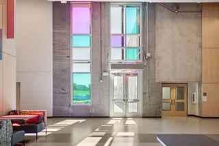 sun shining in through colored windows on an exposed concrete interior wall