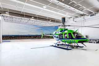photo of helicopter in a heliport garage with garage door open