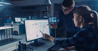 two engineers pointing at floor plans on a computer screen